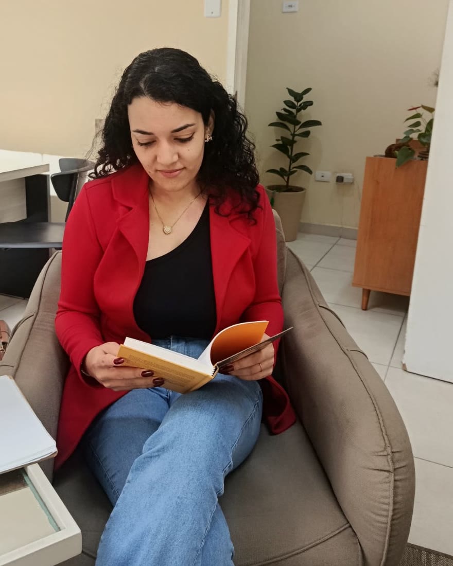Andreza Furtado Carvalho lendo na poltrona do consultório onde atende.