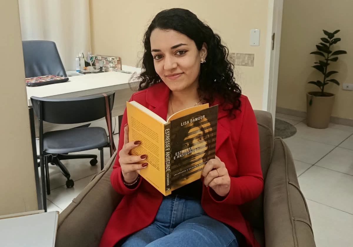 Andreza na poltrona de atendimento do consultório em Suzano, com a escrivaninha e uma planta ao fundo.